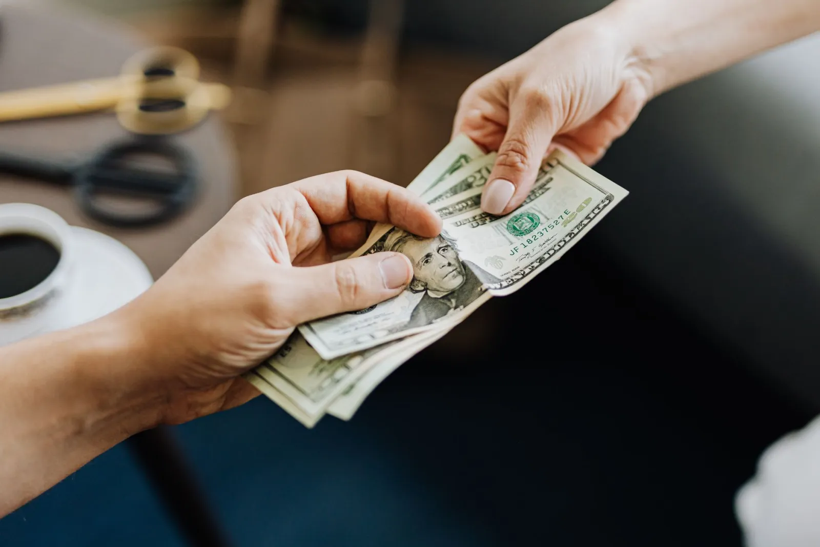 One hand passing cash to another across a table