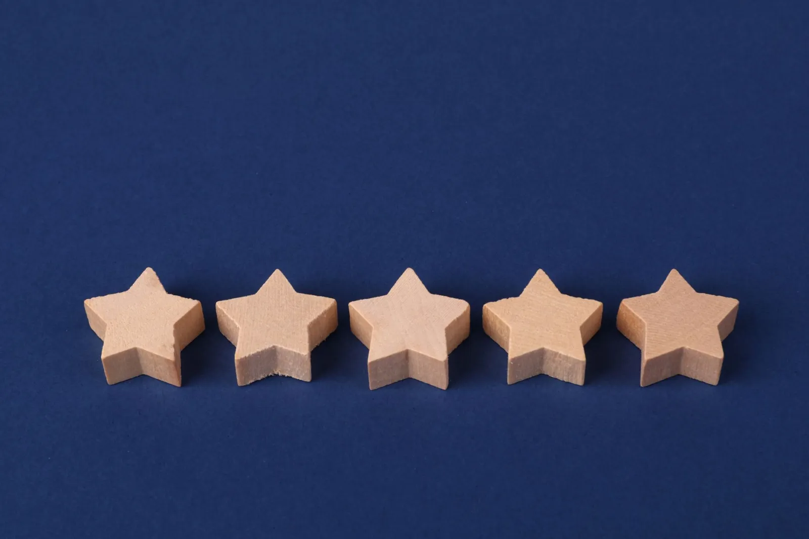 Five wooden stars lined up on a navy background, a five-star client rating
