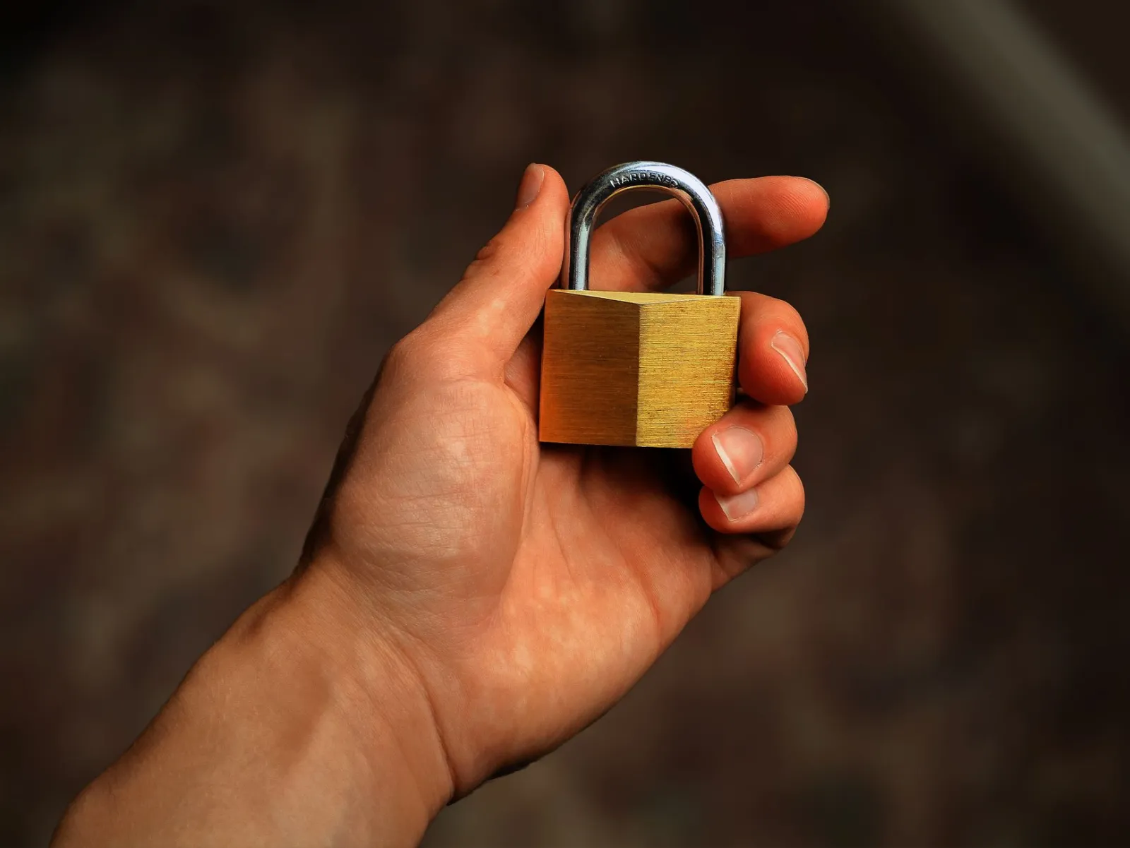 Hand holding a closed brass padlock