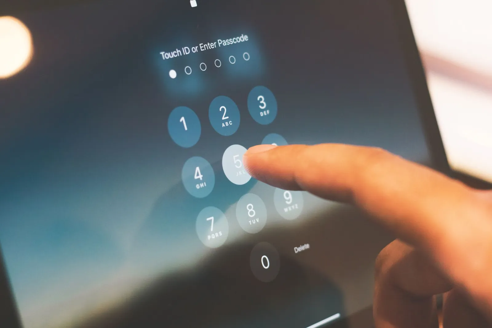 Finger entering a passcode on a phone lock screen