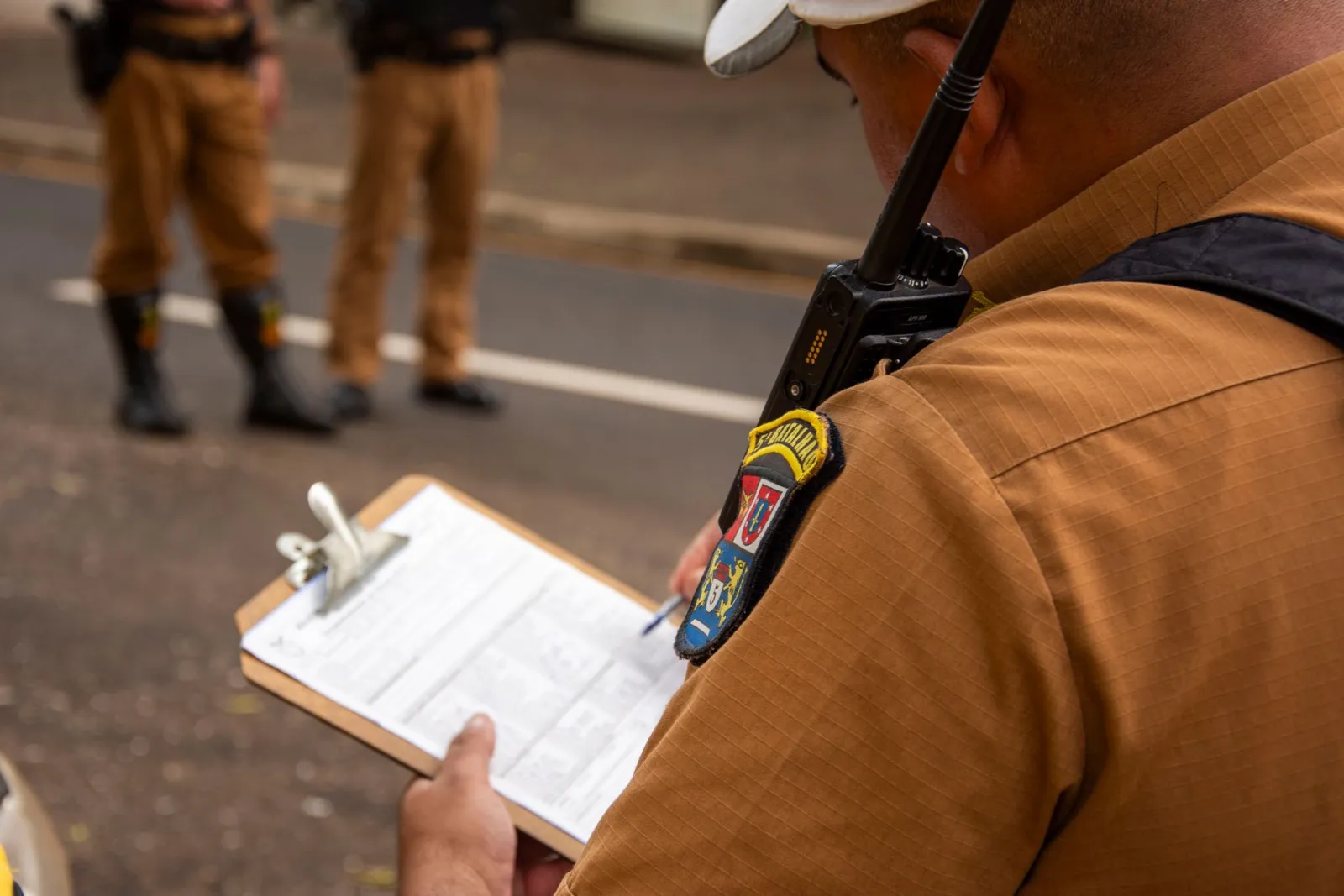 Police officer holding a clipboard while taking a written report