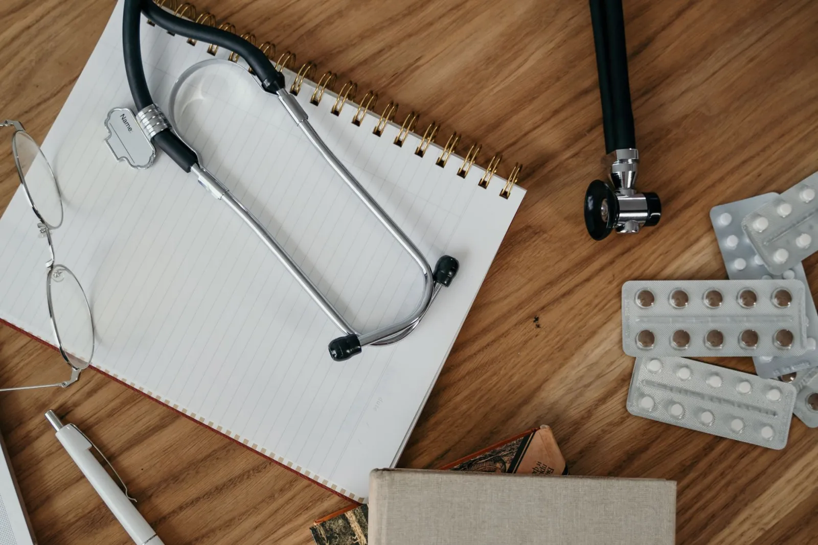 Stethoscope, notebook and medicine packs on a desk