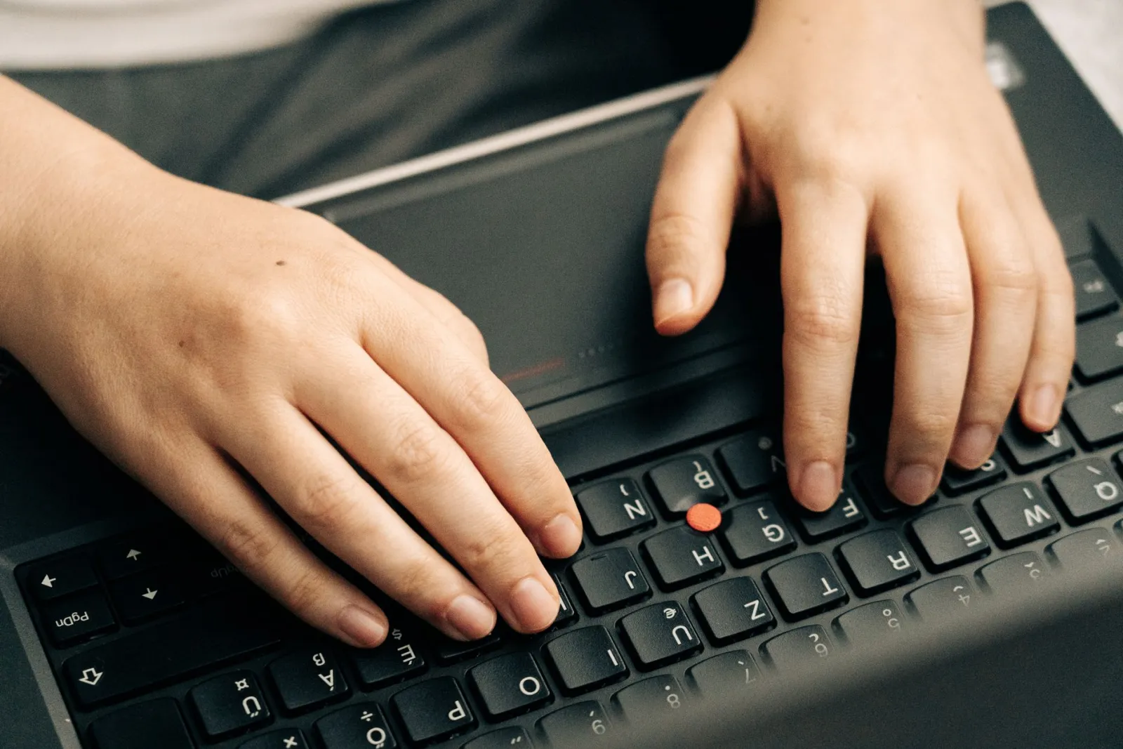 Hands typing a question on a laptop keyboard