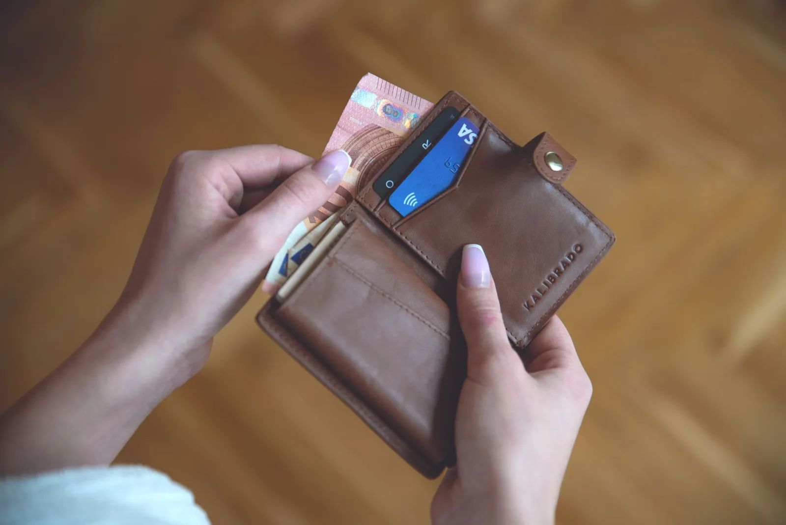 Hands taking a credit card out of a leather wallet